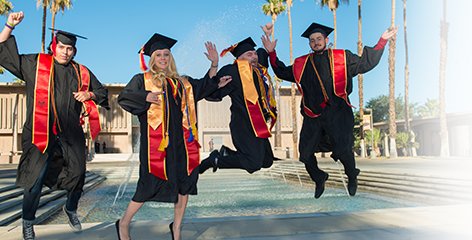 Graduates jumping for joy in front of Fountain of Knowledge