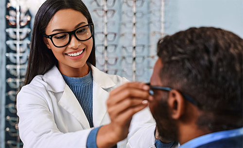 Optician placing glasses on customer